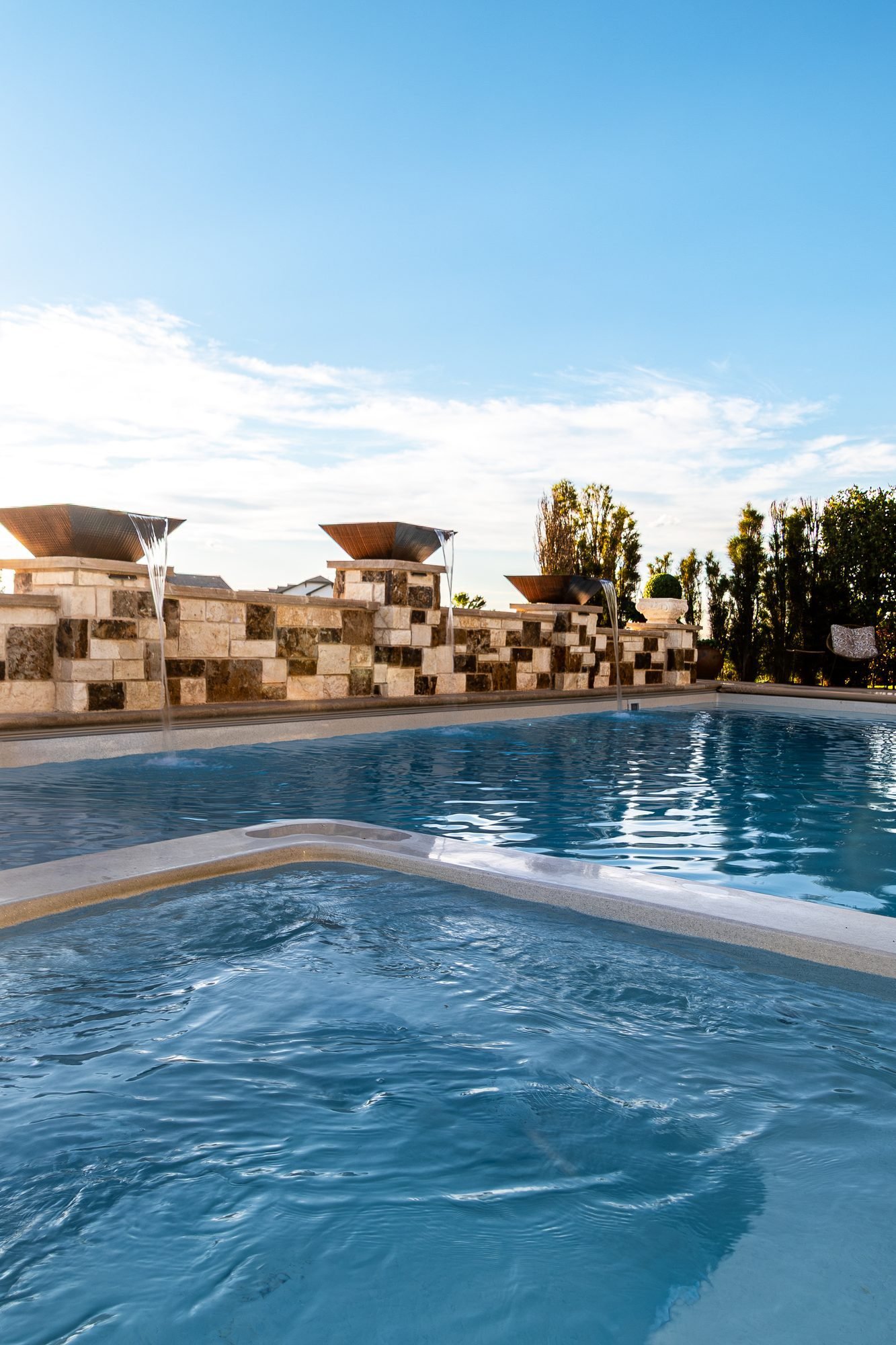 Custom pool and raised spa with stone water feature wall, Colorado landscape design