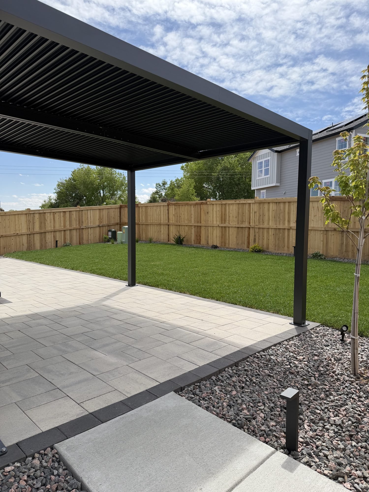 Modern paver patio with louvered pergola and fresh turf, Colorado outdoor living