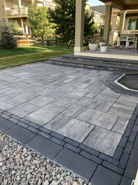 Large-format gray paver patio with a double charcoal paver border and fire pit, installed by Oro Landscape